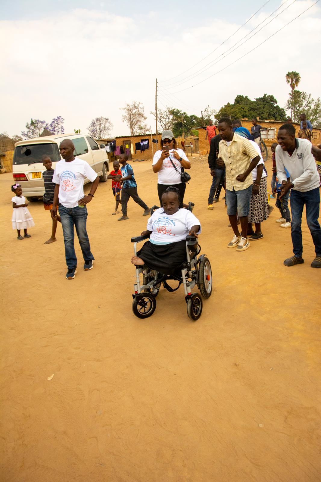 Community members gathered around the wheelchair recipient