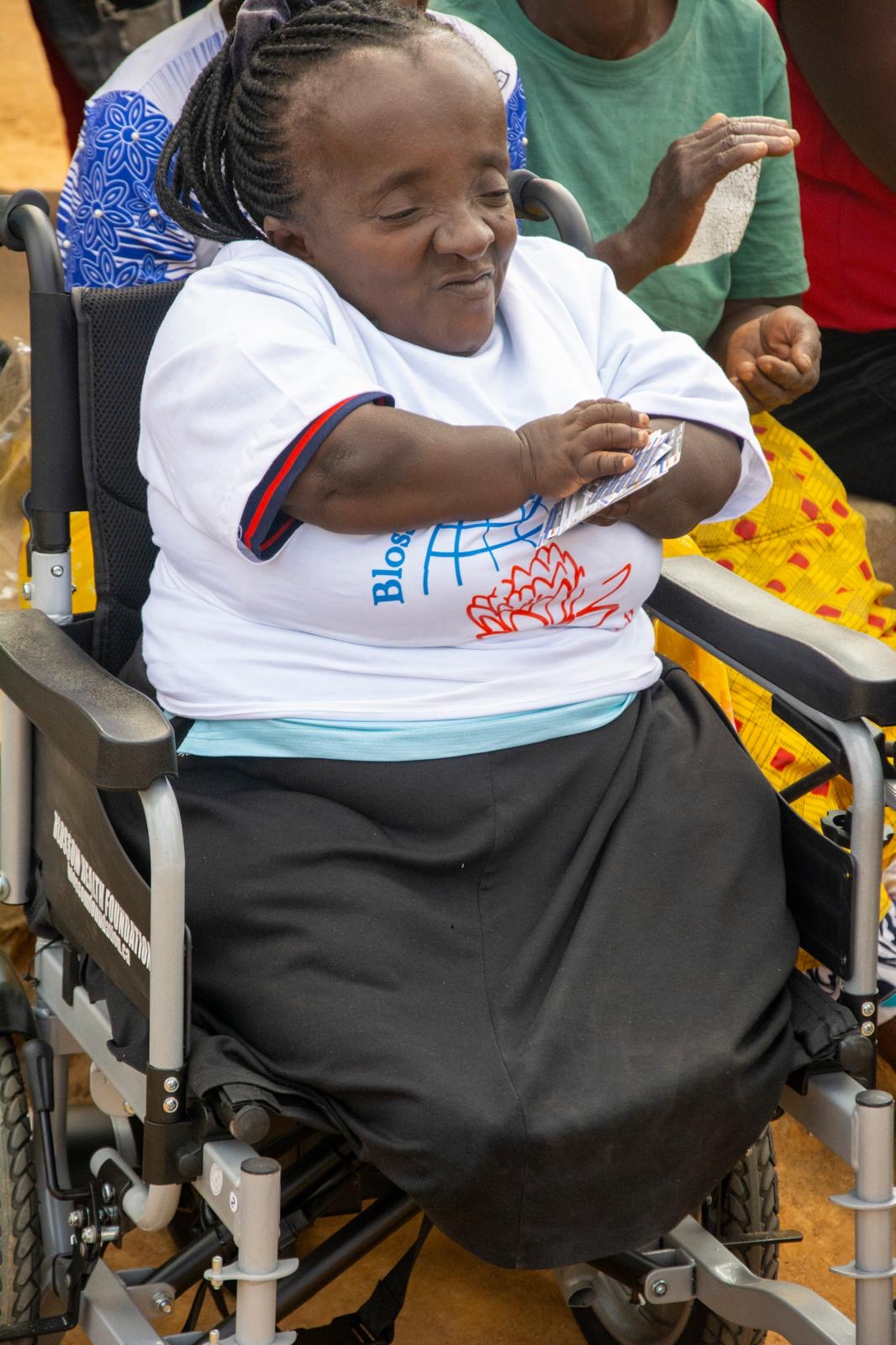 Close-up photograph of the wheelchair recipient wearing a Blossom Health Foundation shirt